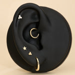 Ear with gold earrings on a beige background