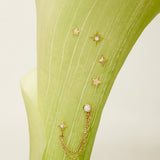 Gold star-shaped earrings with chains on a green fabric background