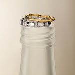 The Bamboo Chunky Crystal Ring in Silver is displayed stacked on the frosted neck of a glass bottle, set against a neutral beige background.