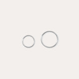 The 14K Solid White Gold 20G Mini Clicker, shown in two shiny sizes on a plain white background, is perfect for use as a clicker or nose ring.
