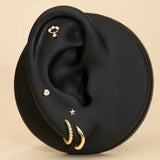 Black ear with gold earrings on a beige background with solid gold flatback studs