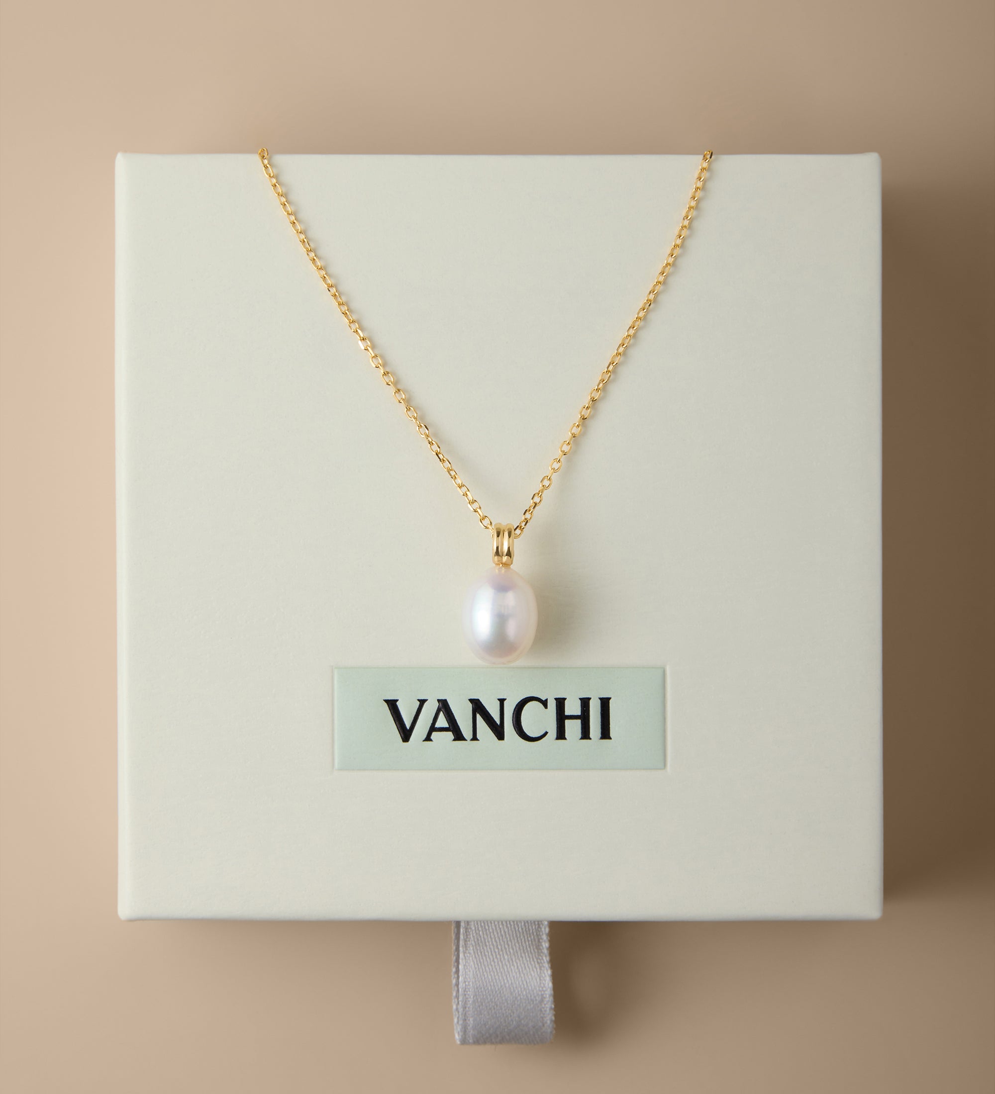 A Freshwater Pearl Necklace in Silver is displayed on a cream-colored VANCHI box, set against a beige background. The elegant design features an adjustable slider chain for the perfect fit.