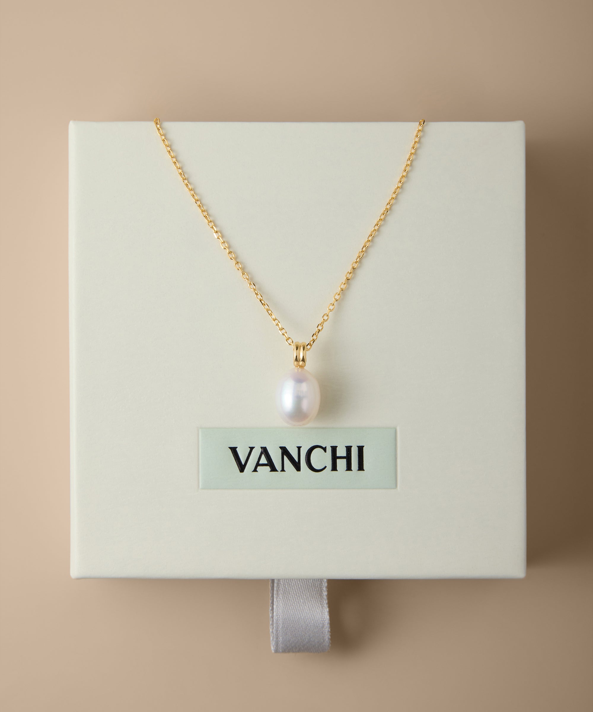 A Freshwater Pearl Necklace in Silver is displayed on a cream-colored VANCHI box, set against a beige background. The elegant design features an adjustable slider chain for the perfect fit.