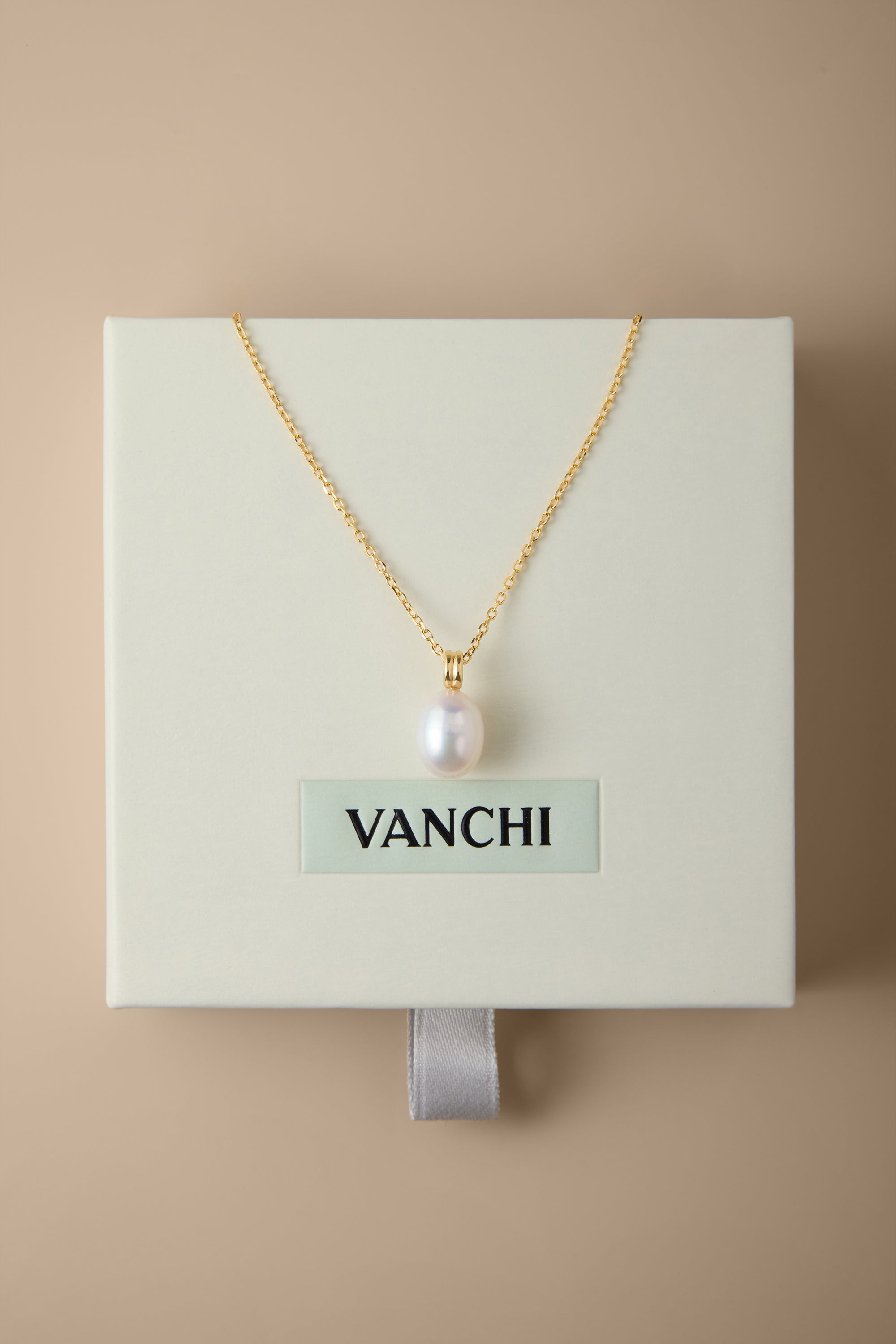 A Freshwater Pearl Necklace in Silver is displayed on a cream-colored VANCHI box, set against a beige background. The elegant design features an adjustable slider chain for the perfect fit.