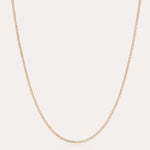 The Alba Tennis Necklace in Gold features a thin, simple design with fine links and a subtle shine, shown in a gentle curve against a light background.