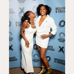 Two women smile in front of a Noughts + Crosses and BBC iPlayer backdrop. One wears a white dress; the other pairs her white suit with the Nola Pavé Triple Band Ring in Silver for added sparkle.