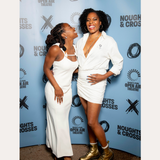 Two women smile in front of a Noughts + Crosses and BBC iPlayer backdrop. One wears a white dress; the other pairs her white suit with the Nola Pavé Triple Band Ring in Silver for added sparkle.