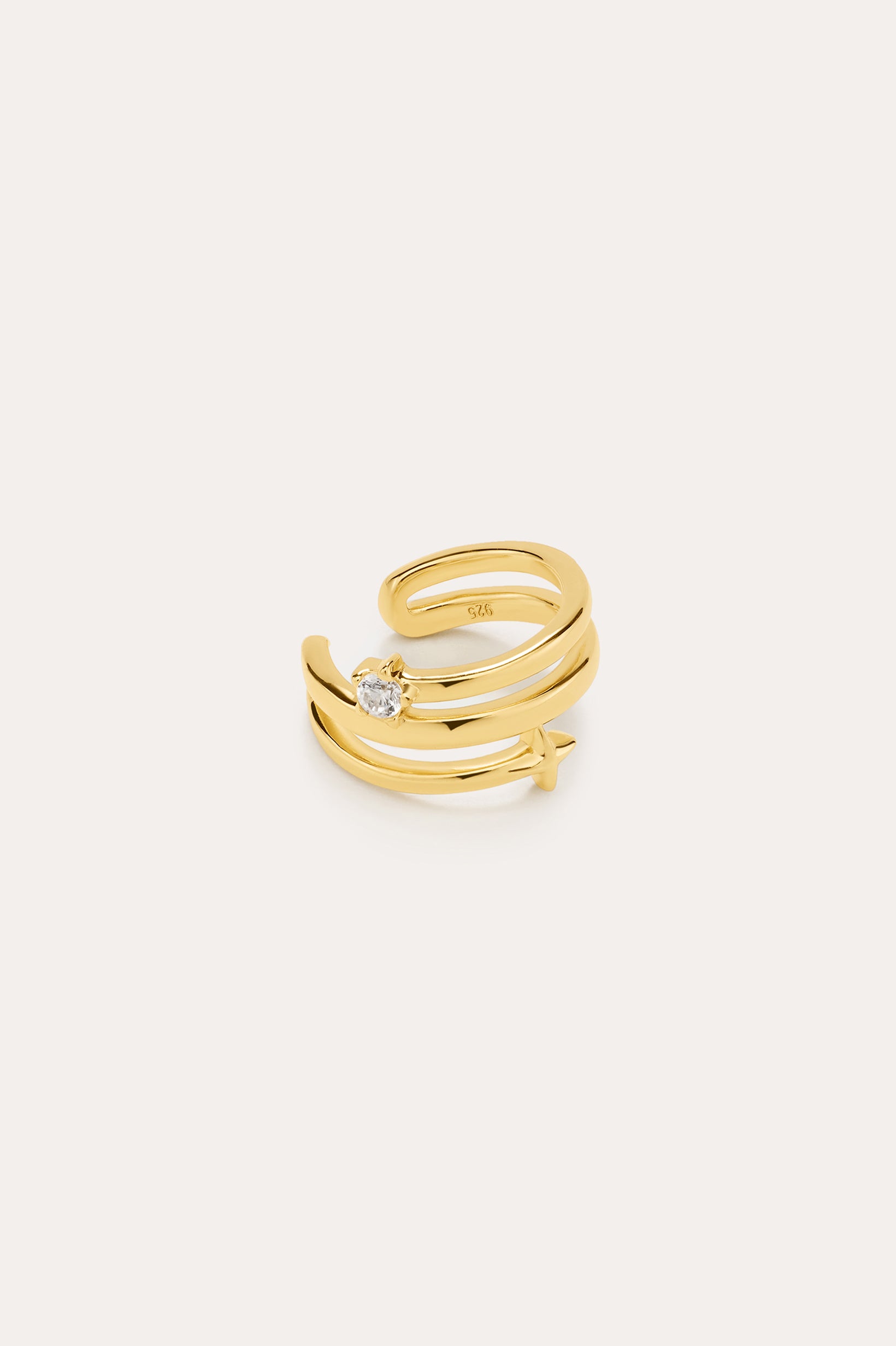 The Star Crystal Ear Cuff in Gold features a wrap-around design in 18k gold plating, adorned with a small crystal star and a clear round gemstone. This celestial accessory is displayed on a plain light beige background.