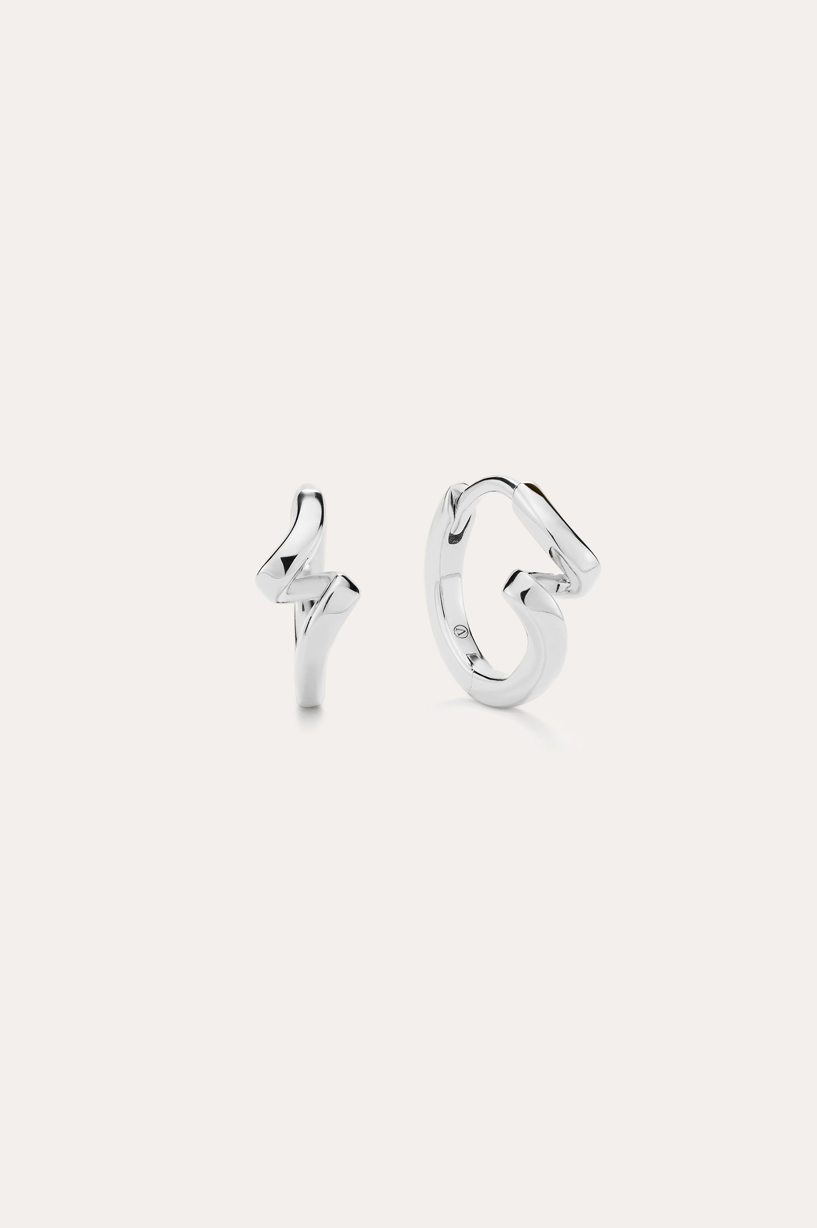 A pair of Ribbon Twist Huggies in sterling silver—one shaped like a lightning bolt, the other with a smooth, twisted ribbon design—are displayed against a plain white background.