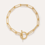 The Paperclip Toggle Bracelet in Gold, crafted in 18k gold plated finish with elongated oval links and a twisted toggle clasp, is shown against a plain light background.