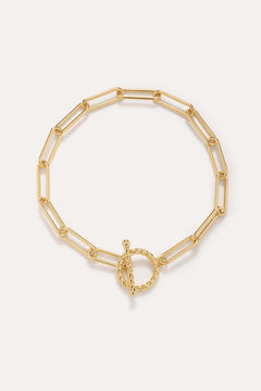 The Paperclip Toggle Bracelet in Gold, crafted in 18k gold plated finish with elongated oval links and a twisted toggle clasp, is shown against a plain light background.