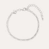 The Figaro And Box Chain Layered Bracelet in Sterling Silver features an adjustable extension, lobster clasp, and a small geometric charm. Shown on a light background, this delicate bracelet is perfect for everyday wear.
