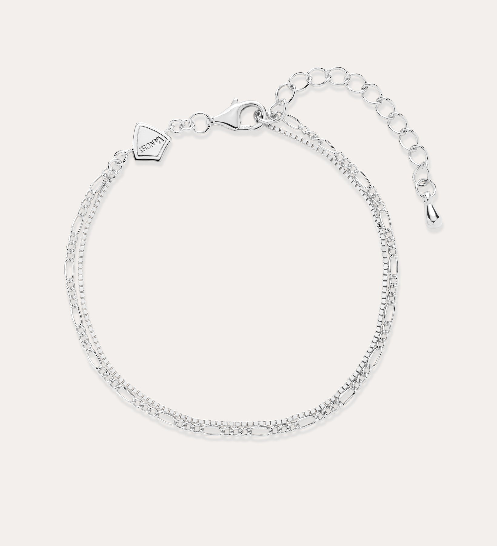 The Figaro And Box Chain Layered Bracelet in Sterling Silver features an adjustable extension, lobster clasp, and a small geometric charm. Shown on a light background, this delicate bracelet is perfect for everyday wear.