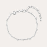 The Pia Crystal Link Bracelet in Sterling Silver features a twist chain with small clear crystals, an adjustable extension, a lobster clasp, and a heart-shaped charm near the clasp.