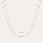 The Figaro And Box Chain Layered Necklace in Sterling Silver features a fine box chain and a longer Figaro link, both displayed against a plain white background for an elegant layered look.