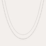 The Figaro And Box Chain Layered Necklace in Sterling Silver features a fine box chain and a longer Figaro link, both displayed against a plain white background for an elegant layered look.