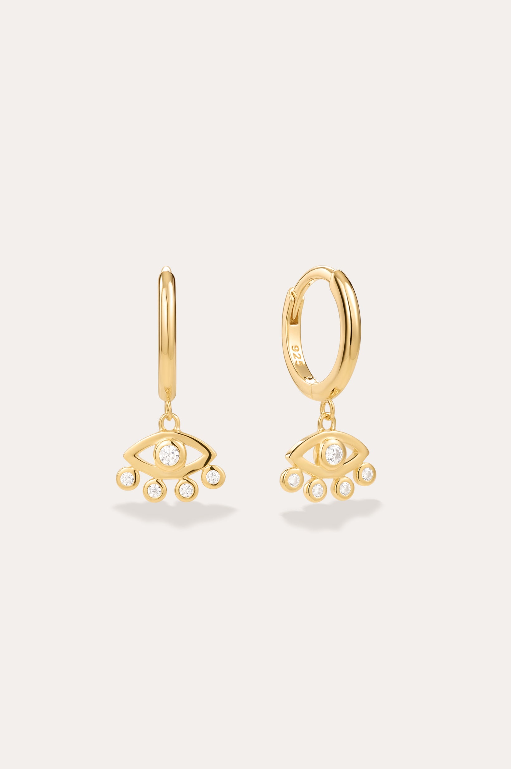 Defender Evil Eye Hoops in 18k Gold Plated, featuring dangling evil eye charms with a central clear stone and four smaller stones on the bottom edge, showcased as unique spiritual jewelry against a plain light background.