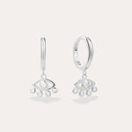 Defender Evil Eye Hoops in Sterling Silver featuring hoops with dangling stylized eye charms, each set with a central clear gemstone and three smaller stones below. Displayed against a light, plain background.