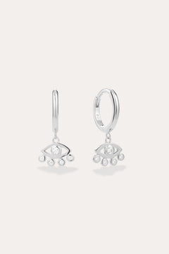 Defender Evil Eye Hoops in Sterling Silver featuring hoops with dangling stylized eye charms, each set with a central clear gemstone and three smaller stones below. Displayed against a light, plain background.