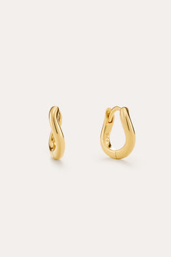 The Nori Mini Twisted Huggies in Gold are 18k gold plated earrings with a smooth, twisted design, beautifully shown on a light beige background.