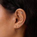 Close-up of a woman's ear adorned with the Chain Clicker Titanium Ring in Gold and multiple studs—an ideal look for highlighting hypoallergenic earrings.