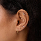 Close-up of a woman's ear adorned with the Chain Clicker Titanium Ring in Gold and multiple studs—an ideal look for highlighting hypoallergenic earrings.
