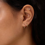 Close-up of a woman's ear with dark hair and tan skin, wearing 14K Recycled Solid Yellow Gold Plain Huggie Earring and diamond butterfly stud—an elegant display of sustainable fine jewellery.