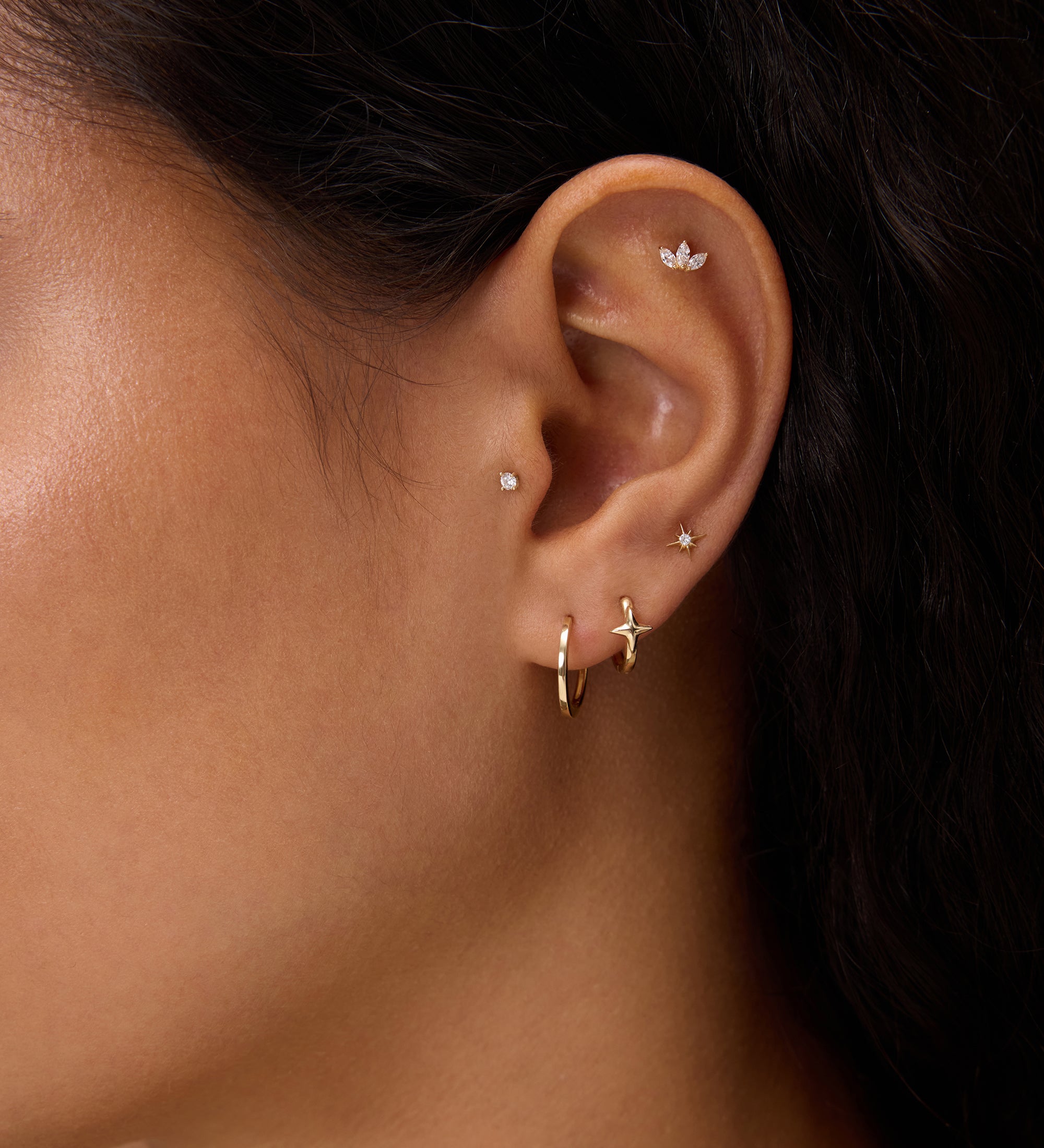 Close-up of a woman's ear with dark hair and tan skin, wearing 14K Recycled Solid Yellow Gold Plain Huggie Earring and diamond butterfly stud—an elegant display of sustainable fine jewellery.