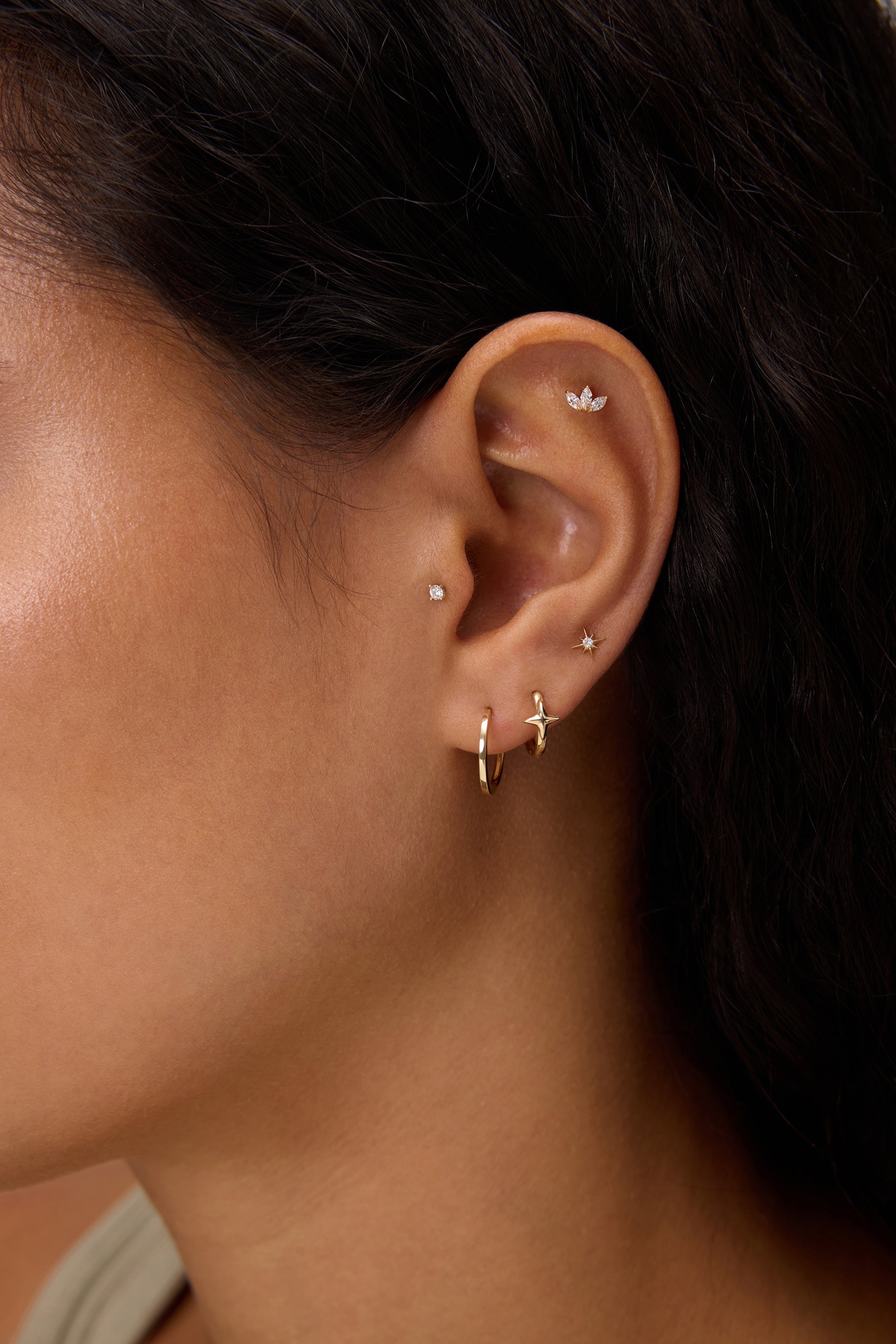 Close-up of a woman's ear with dark hair and tan skin, wearing 14K Recycled Solid Yellow Gold Plain Huggie Earring and diamond butterfly stud—an elegant display of sustainable fine jewellery.