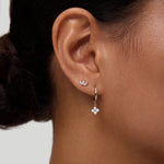Close-up of a woman's ear wearing the Flora Crystal Charm Huggies in Gold, featuring sparkling cubic zirconia and a gold-plated finish, set against a plain background.