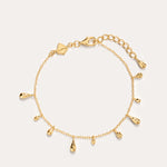 The Rhea Molten Cascade Bracelet in Gold features small teardrop-shaped charms with a subtle hammered texture, each charm evenly spaced along the 14K gold plated chain and finished with an adjustable clasp, displayed on a plain light background.