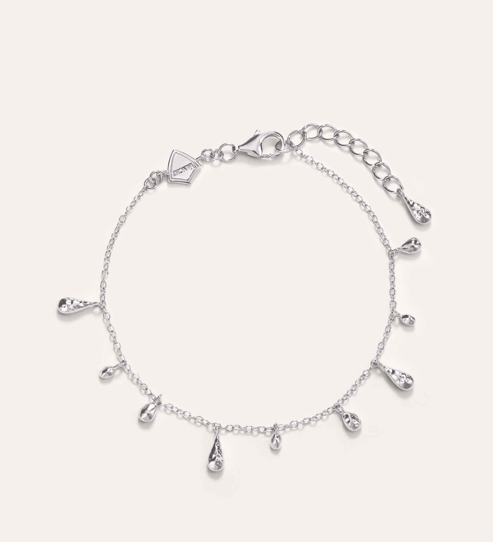The Rhea Molten Cascade Bracelet in Silver features delicate rhodium-plated teardrop charms evenly spaced along a slender chain, complete with an adjustable clasp and extra extension links—ideal as a dainty stand-alone piece or layered for a chic, stacked style.
