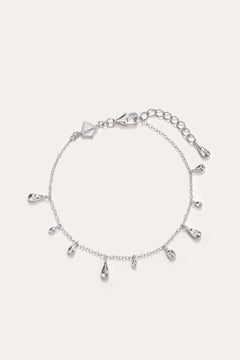 The Rhea Molten Cascade Bracelet in Silver features delicate rhodium-plated teardrop charms evenly spaced along a slender chain, complete with an adjustable clasp and extra extension links—ideal as a dainty stand-alone piece or layered for a chic, stacked style.