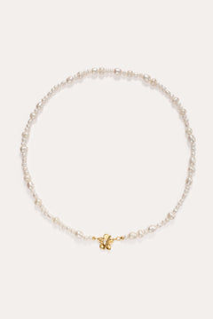 The Flora Multi Pearl Toggle Choker in Gold features irregularly shaped white freshwater pearls and a small 14K gold plated butterfly charm at the center, finished with a floral toggle clasp and displayed on a plain white background.