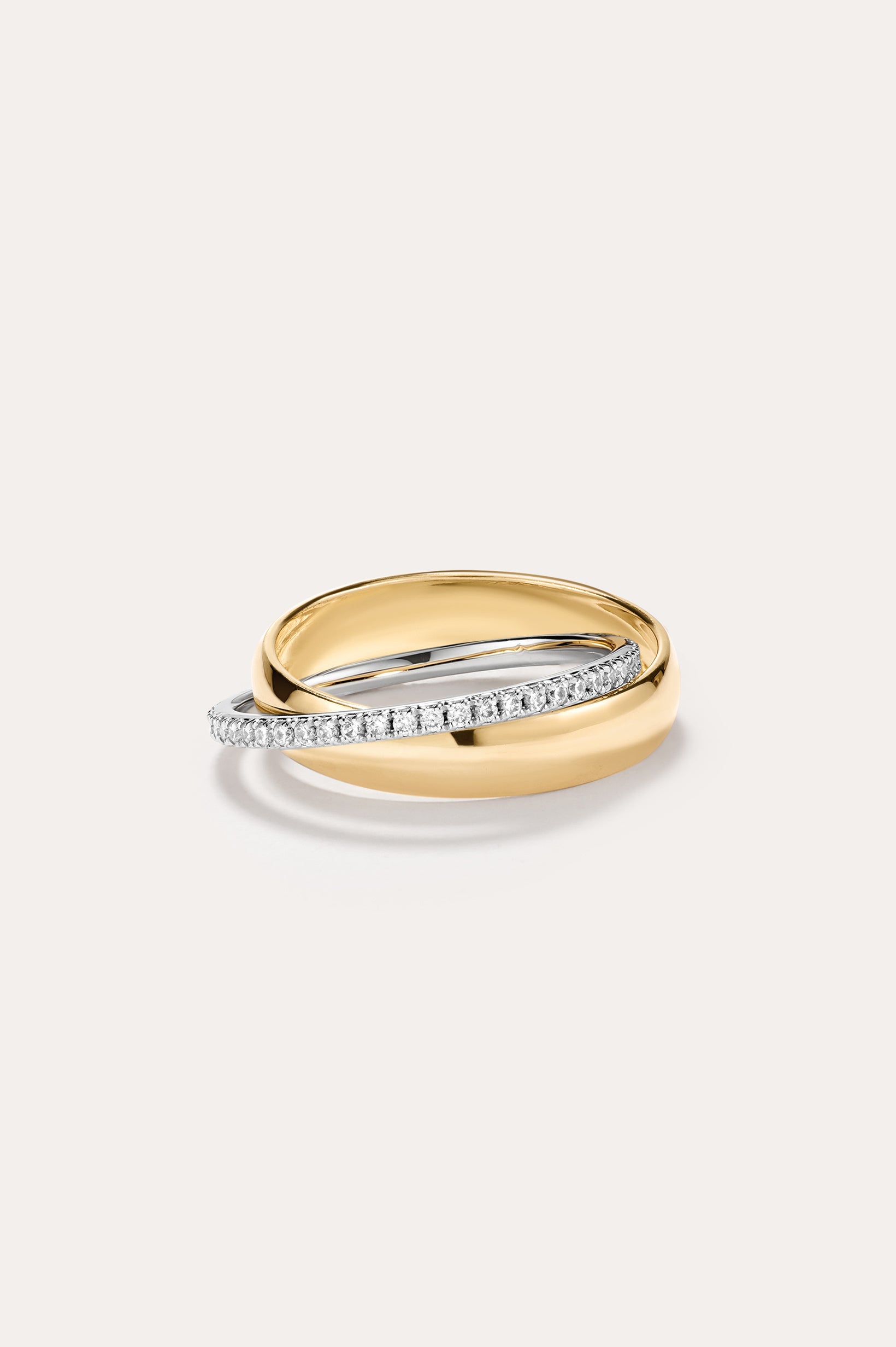 The Mixed Metal Interlocking Ring, featuring a 14K gold plated band intertwined with a slender silver band adorned with small diamonds and sparkling cubic zirconia, creates a modern, stylish statement against a plain light background.