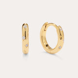The Starfall Huggies in Gold are a pair of small, 14K gold plated hoops featuring three round clear cubic zirconia stones set within star-shaped engravings—an elegant touch that brings sparkle to any look.