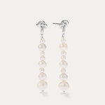 Introducing the Knot Multi Pearl Drop Earrings in Sterling Silver: this pair features a row of lustrous white freshwater pearls in varying sizes, elegantly set on sterling silver posts and showcased against a plain light background.