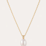 A 14K gold plated chain necklace, featuring a single round white freshwater pearl pendant at its center, is displayed on a plain light background. The Freshwater Pearl Necklace in Gold includes an adjustable slider chain for a perfect fit with any neckline.