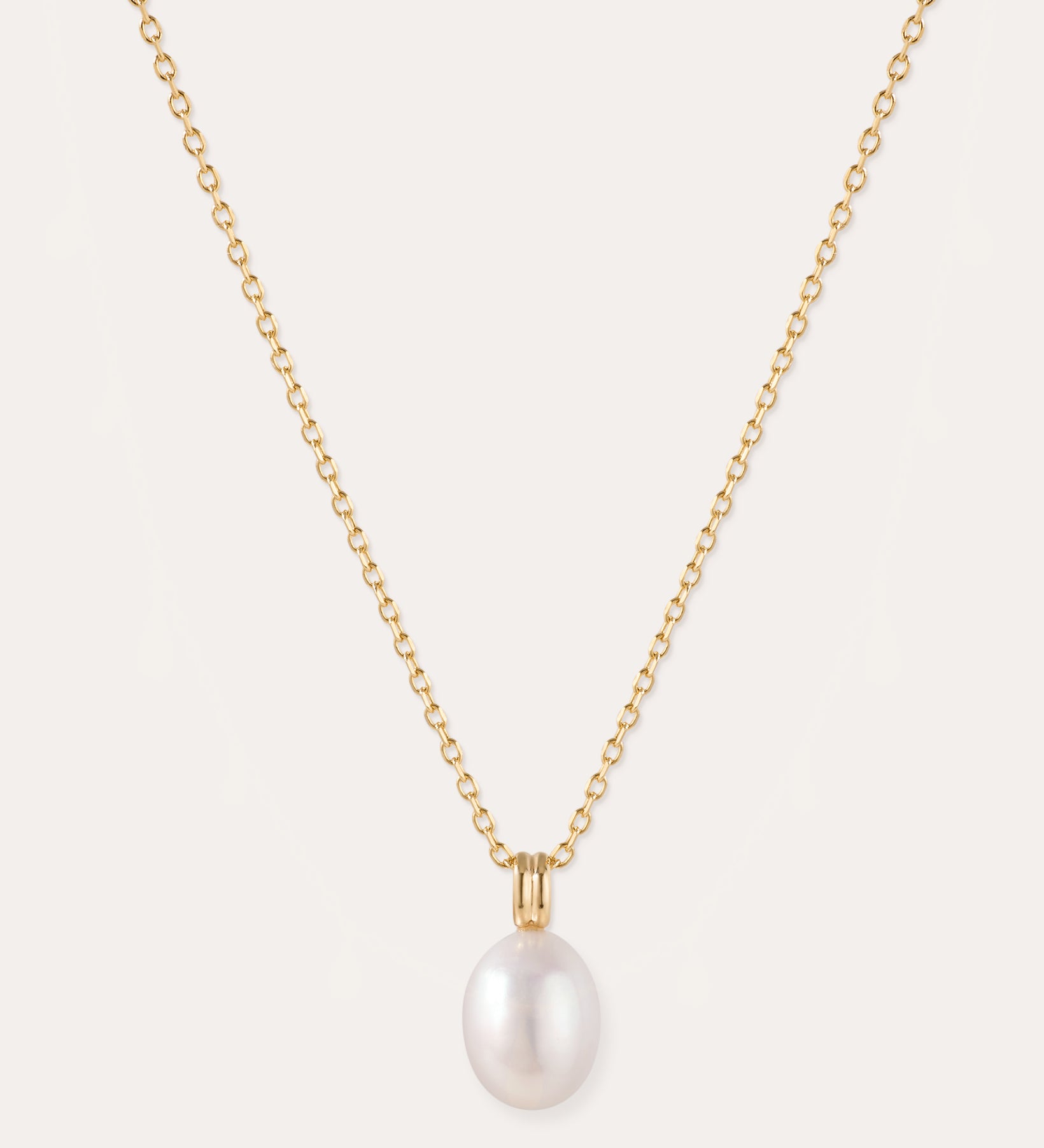 A 14K gold plated chain necklace, featuring a single round white freshwater pearl pendant at its center, is displayed on a plain light background. The Freshwater Pearl Necklace in Gold includes an adjustable slider chain for a perfect fit with any neckline.