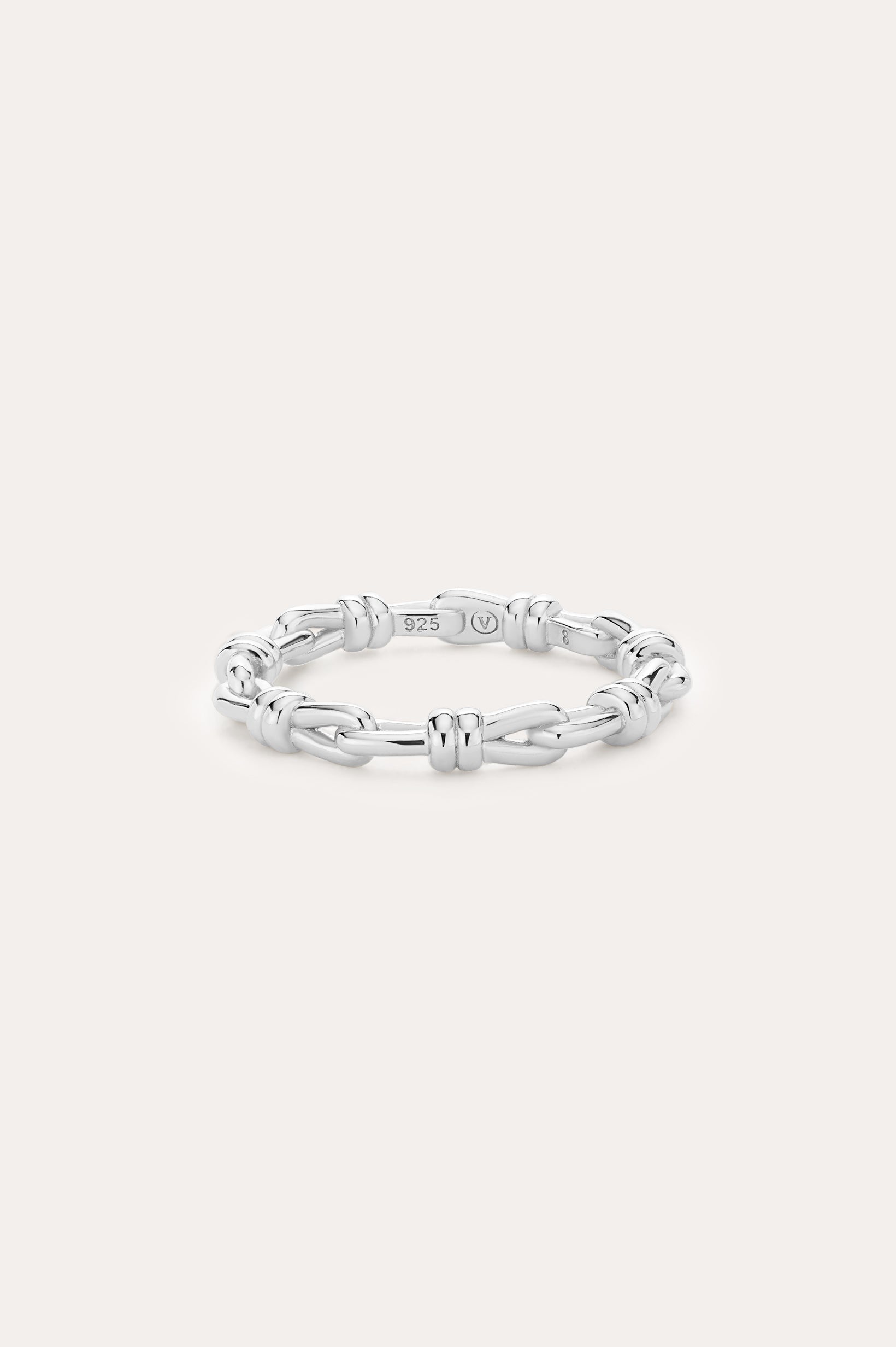 Introducing the Noa Link Ring in Silver: a thin sterling silver band featuring a series of chain-inspired, knot-like links evenly spaced around its circumference. Shown against a plain, light background, this elegant piece is the perfect stacking ring for any collection.