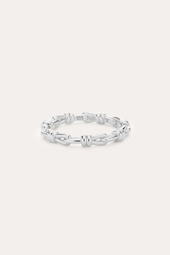 Introducing the Noa Link Ring in Silver: a thin sterling silver band featuring a series of chain-inspired, knot-like links evenly spaced around its circumference. Shown against a plain, light background, this elegant piece is the perfect stacking ring for any collection.