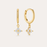 The Flora Crystal Charm Huggies in Gold are 18k gold plated earrings with dangling floral-shaped pendants of five clear gemstones. Shown from both front and side, they display their elegant shine and secure clasp beautifully.