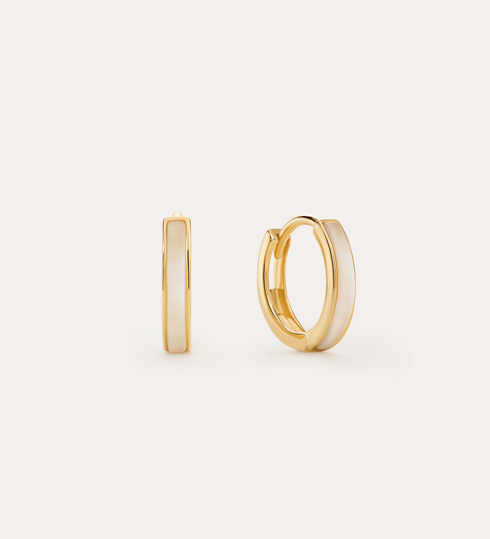 The Mother of Pearl Huggies in Gold are 18k gold-plated small hoops with a glossy white enamel inlay, shown on a light background with one earring facing forward and the other from the side—perfect for everyday jewellery stacks.
