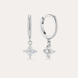 The Flora Crystal Charm Huggies in Sterling Silver feature dangling star-shaped charms with sparkling stones, shown against a plain light background.