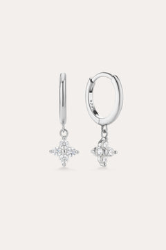 The Flora Crystal Charm Huggies in Sterling Silver feature dangling star-shaped charms with sparkling stones, shown against a plain light background.