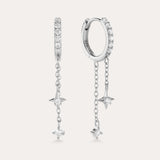 The Star Double Chain Dangle Huggies in Silver feature two sterling silver hoop earrings with star-shaped pendants and cubic zirconia stones along the front for an elegant, sparkling look.