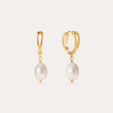 Displayed against a simple light background, the Freshwater Pearl Charm Huggies in Gold feature 14K gold plated hoops, each accented with a single round freshwater pearl—making these elegant earrings an everyday essential.