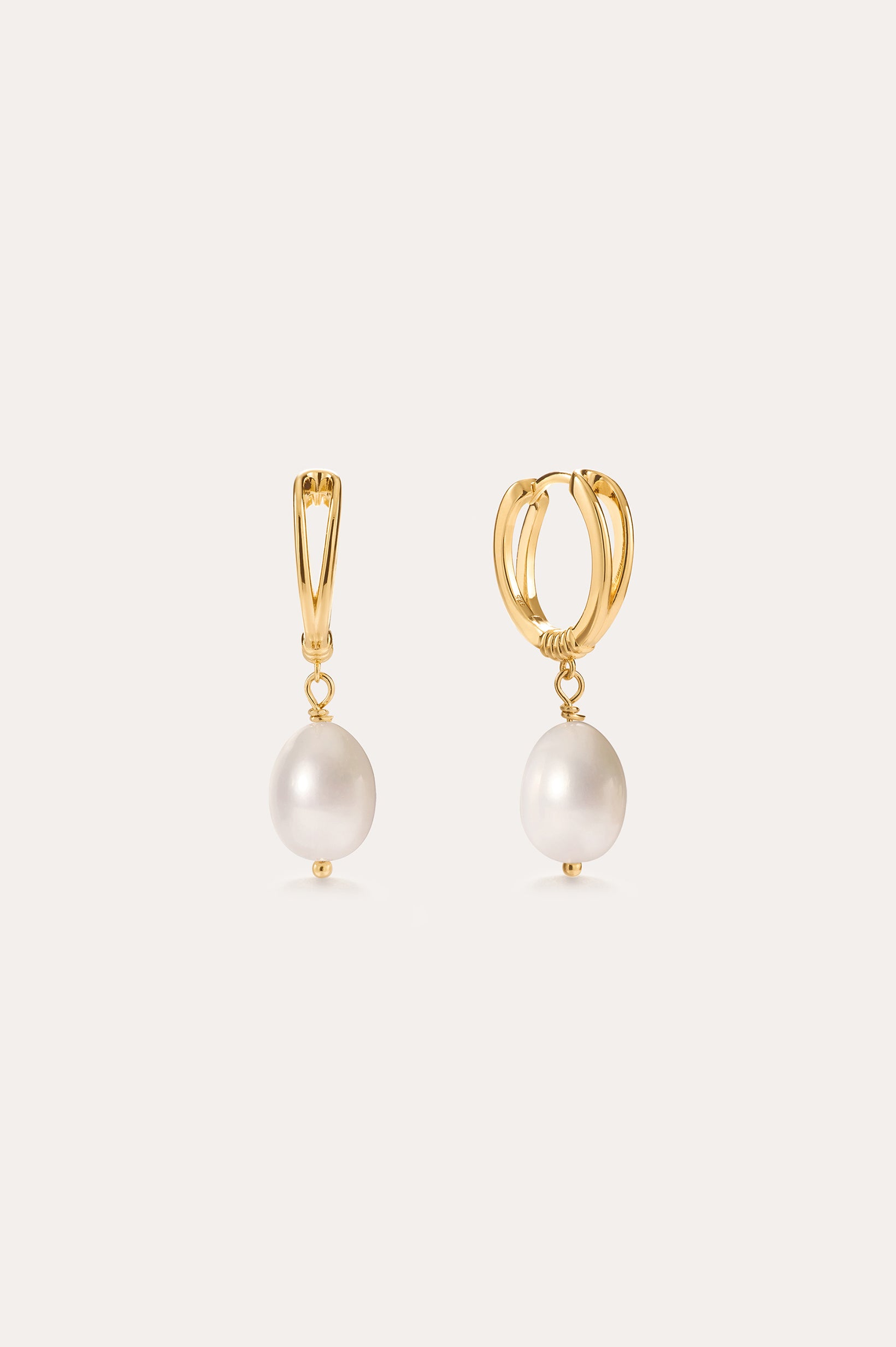 Displayed against a simple light background, the Freshwater Pearl Charm Huggies in Gold feature 14K gold plated hoops, each accented with a single round freshwater pearl—making these elegant earrings an everyday essential.