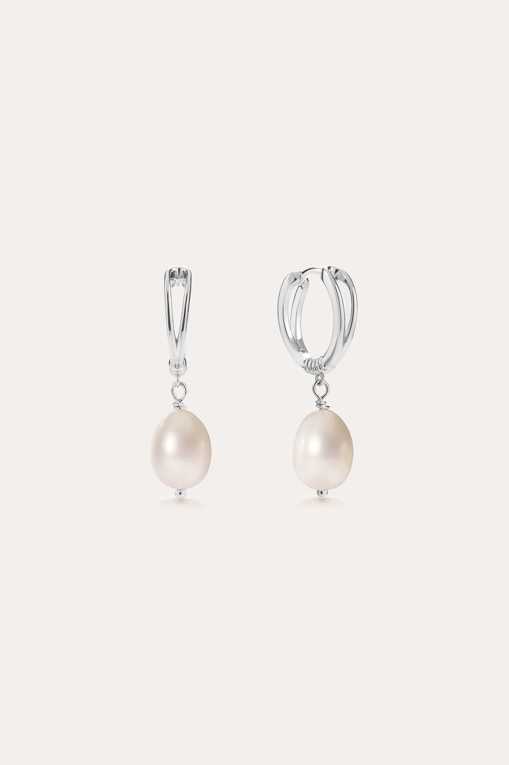 A pair of Freshwater Pearl Charm Huggies in Sterling Silver, each adorned with a single round white freshwater pearl, displayed on a plain light background—these earrings are the perfect everyday essential.