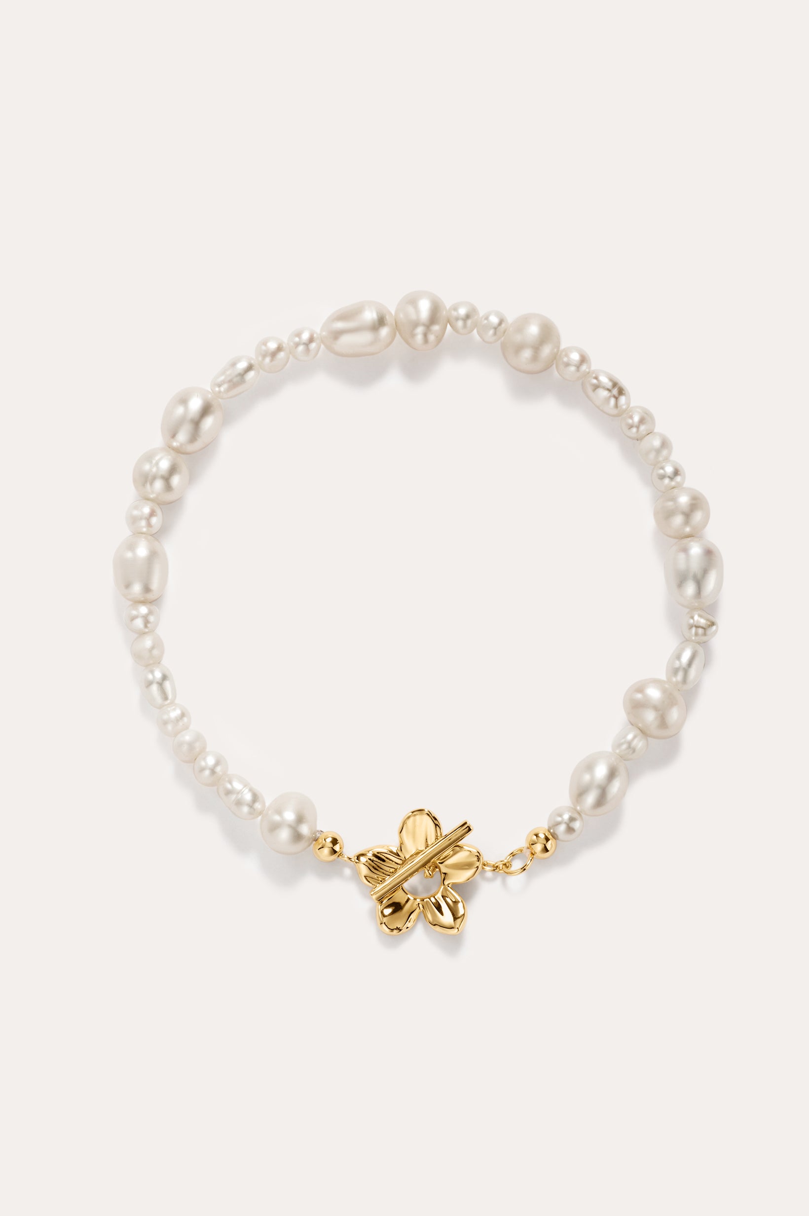 The Flora Multi Pearl Toggle Bracelet in Gold showcases irregular white freshwater pearls and features a 14K gold plated sterling silver butterfly-shaped toggle clasp at the center, elegantly displayed on a light background.